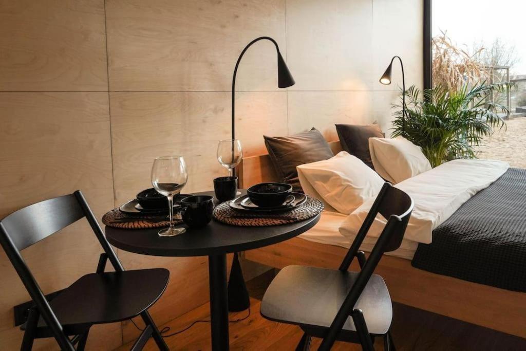 stół i krzesła z kieliszkami do wina i łóżkiem w obiekcie Riverfront Cabins in the garden w Poznaniu