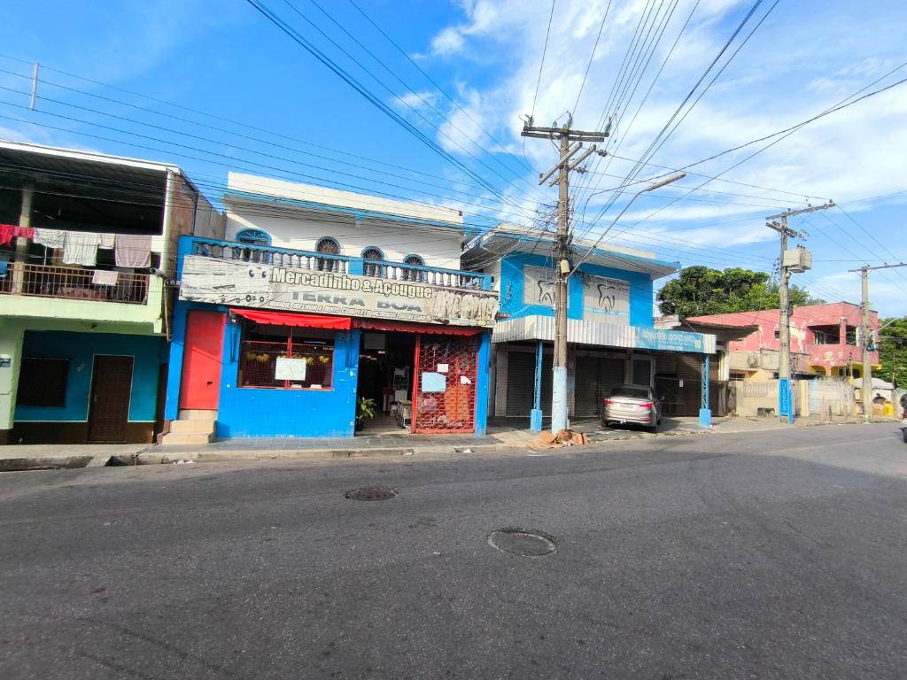una calle con un edificio azul a un lado de la carretera en Quartos econômicos en Manaus