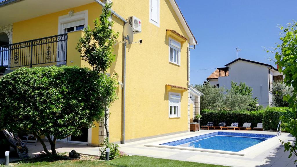 żółty dom z basenem przed nim w obiekcie Ferienhaus Holek w mieście Šilo