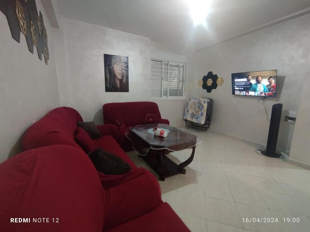 a living room with a red couch and a table at Magnifique appartement au RDC in Casablanca