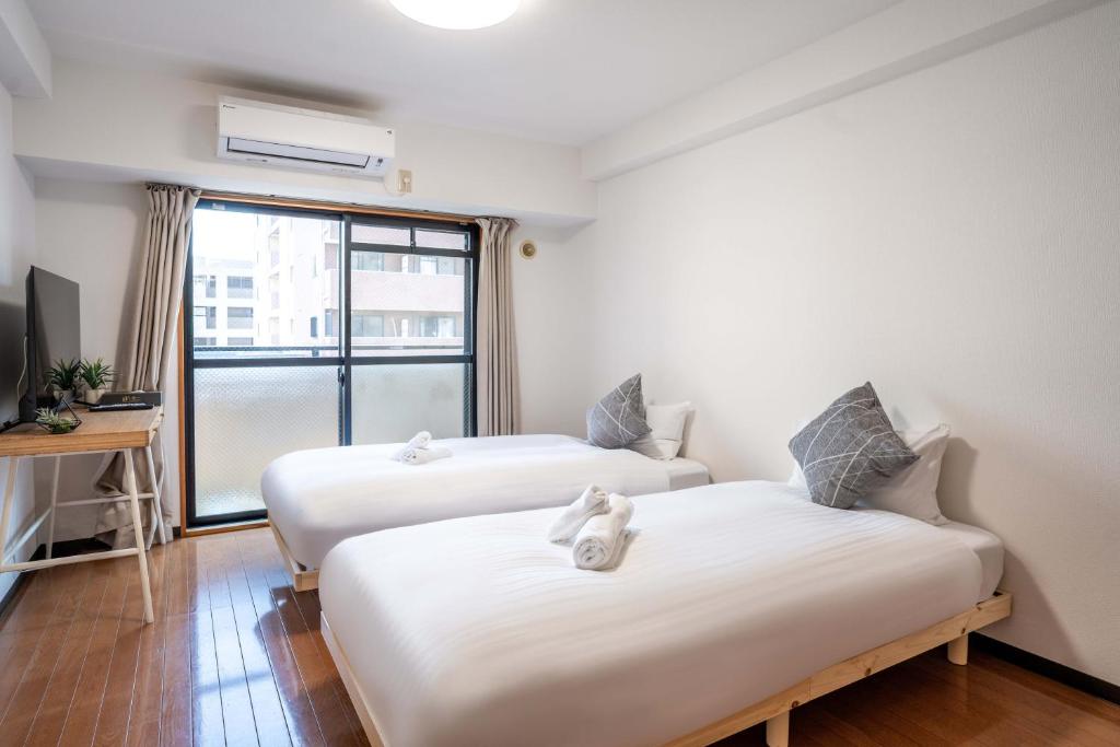 2 Betten in einem Zimmer mit Fenster in der Unterkunft Lite House Shinsaibashi V in Osaka