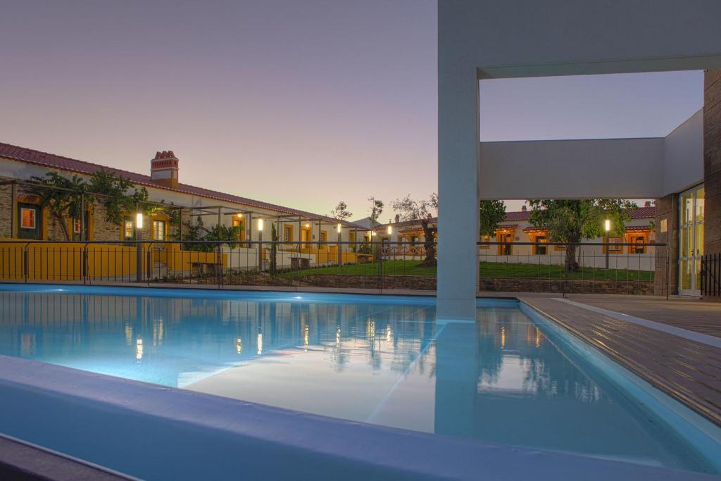 a large swimming pool in front of a building at Herdade da Urgueira in Vale de Pousadas