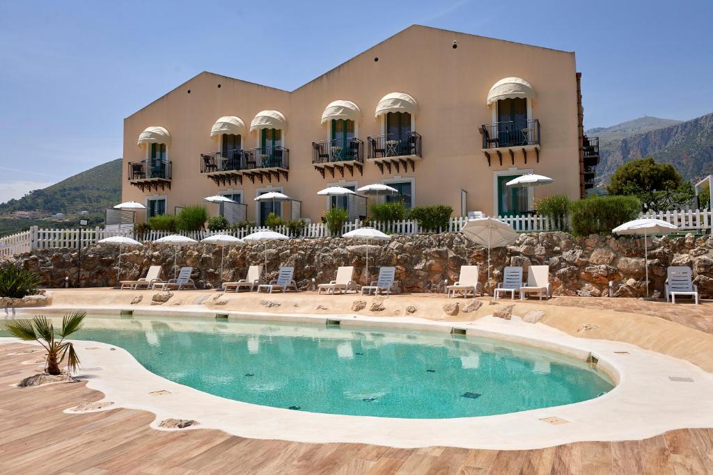 un hotel con piscina frente a un edificio en Baglio Dello Zingaro, en Scopello