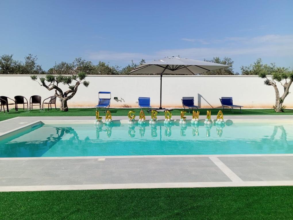 a swimming pool with chairs and an umbrella at Villa La Gardenia in Marsala