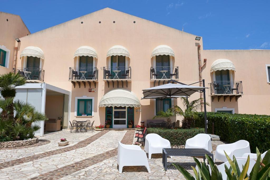 a building with white chairs and an umbrella at Baglio Dello Zingaro in Scopello