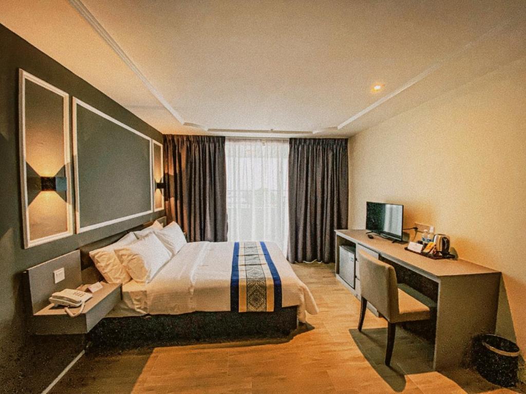 um quarto de hotel com uma cama e uma secretária com um computador em Muar Traders Hotel em Muar