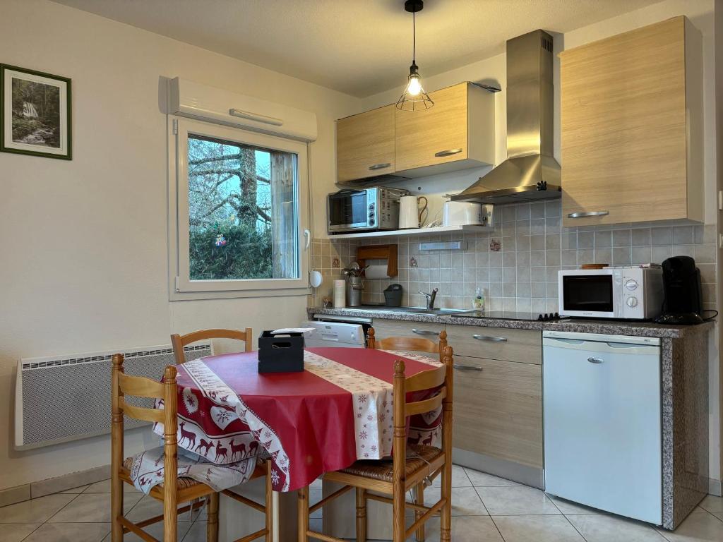 eine Küche mit einem Tisch und einem roten Tischtuch in der Unterkunft Le petit bonhomme de neige in Gérardmer