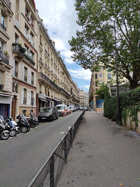 une rue de la ville avec des voitures garées et des bâtiments dans l'établissement Appartement élégant Paris centre, à Paris