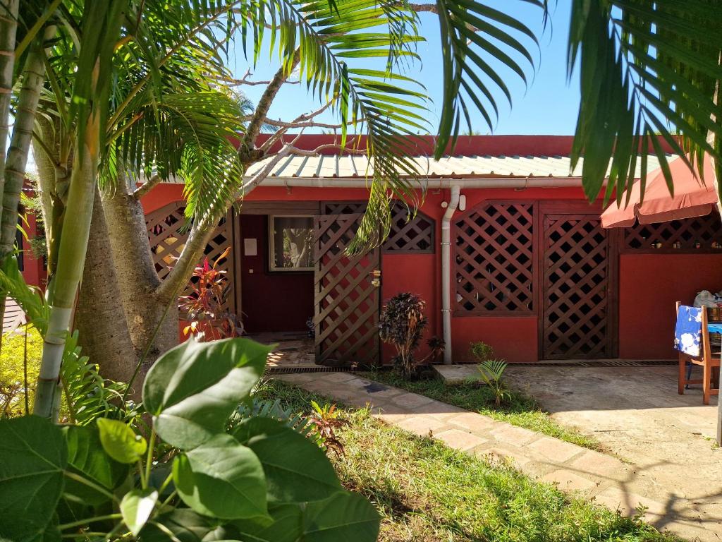une maison rouge avec un palmier devant elle dans l'établissement Bungalow chez Mouch Nosy-Be 2, à Nosy Be