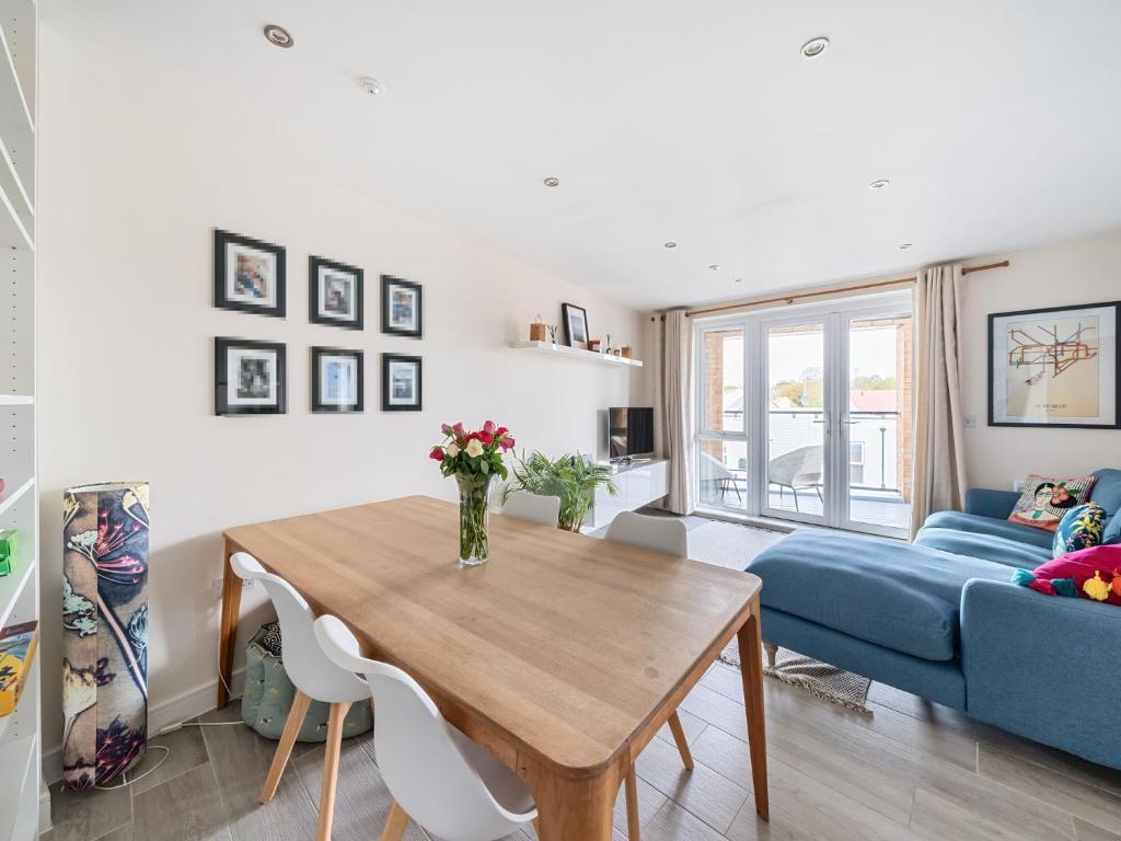 een woonkamer met een houten tafel en een blauwe bank bij Pass the Keys Bright modern flat wparking in Addlestone