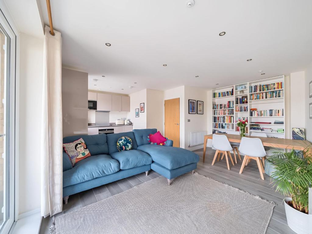 a living room with a blue couch and a kitchen at Spacious Apartment in Addlestone with Free Parking- Pass the Keys in Addlestone