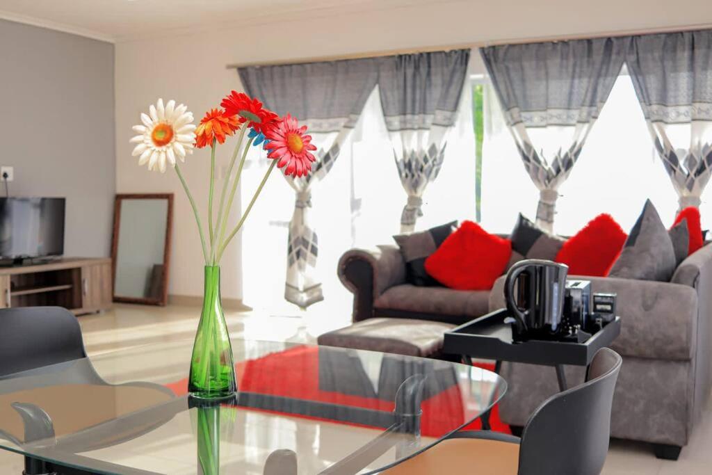 un soggiorno con tavolo in vetro e vaso con fiori di Elegant Poolside Retreat 2-Bed Luxury Guesthouse a Newcastle