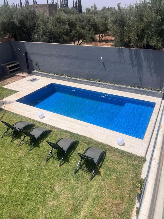 una piscina con 4 sillas y una piscina en Villa Naouma, en Marrakech