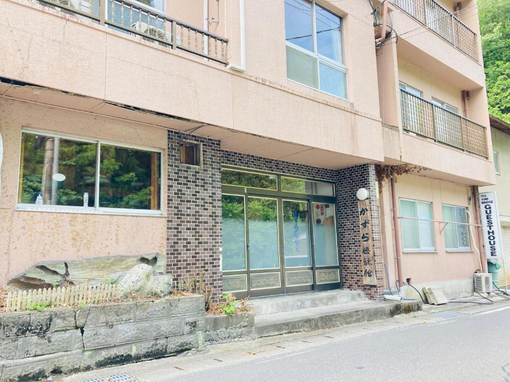 ceglany budynek z dużymi szklanymi drzwiami w obiekcie Guesthouse KAZURABASHI w mieście Miyoshi