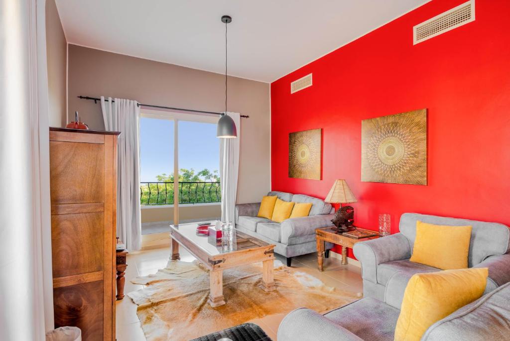 a living room with a red accent wall at Live surrounded by gorgeous Green Golf fields in Ras al Khaimah