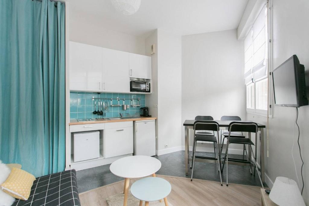 a kitchen with white cabinets and a table and chairs at Le 10 Cosy in Montrouge