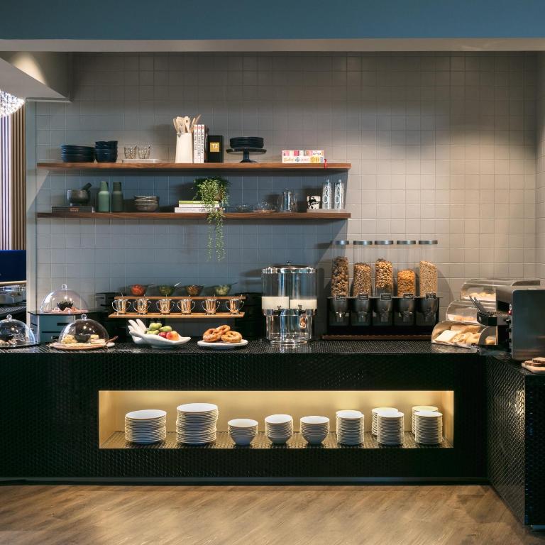 a kitchen with a counter with plates of food at Naumi Auckland Airport Hotel in Auckland