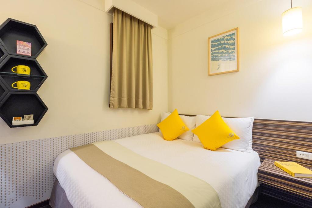 um quarto de hotel com uma cama com almofadas amarelas em Bee House by Cosmos Creation - Taipei Main Station em Taipei