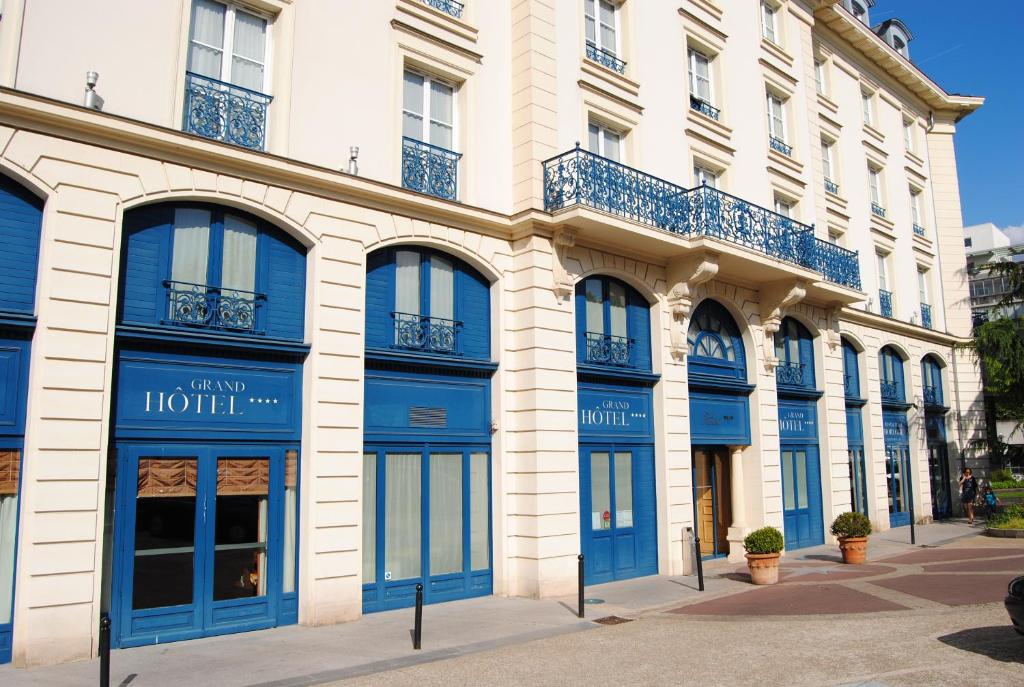 a building with blue doors and windows on a street at Résidence du Grand Hôtel in Le Plessis-Robinson