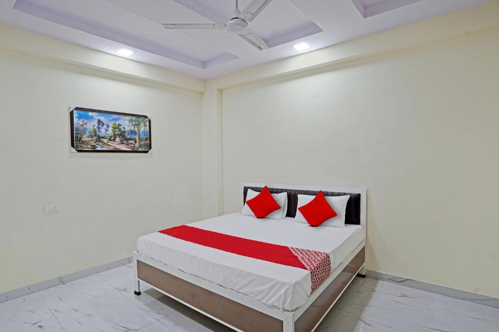 Schlafzimmer mit einem Bett mit roten Kissen und einer Decke in der Unterkunft OYO Flagship Hotel Jojo In in Ghaziabad