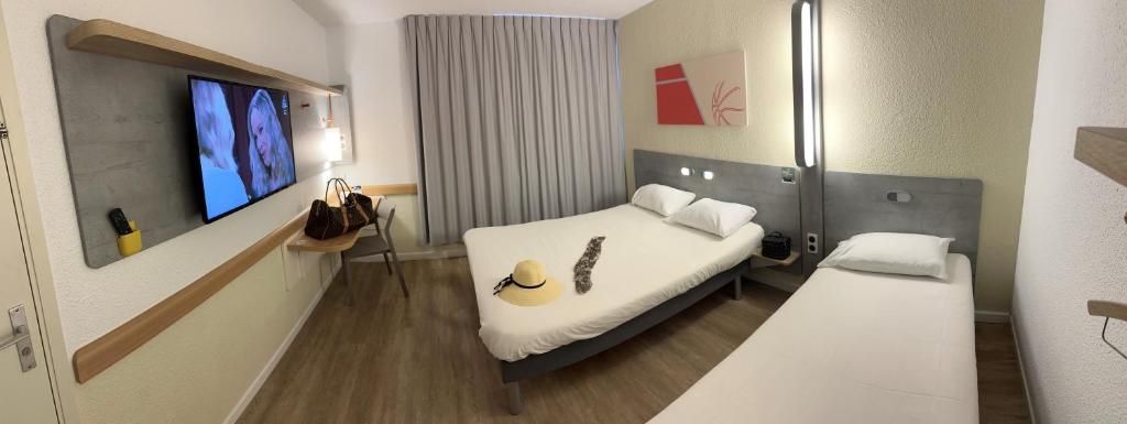 um quarto de hospital com uma cama e uma televisão de ecrã plano em Ibis Budget Fréjus St Raphaël centre et plages à 900m em Fréjus