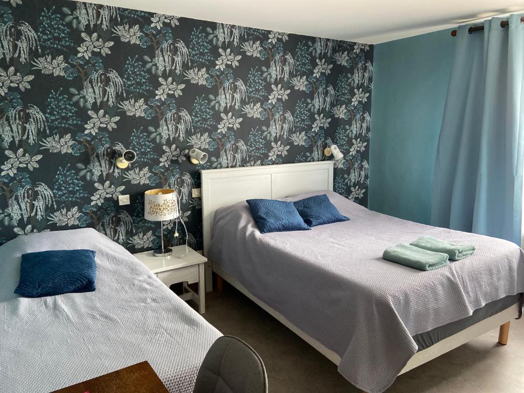 Duas camas num quarto com papel de parede azul e branco em LES TERRASSES DU LAC em Chaumard