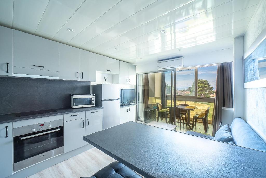 une cuisine avec des armoires blanches et une table et une salle à manger dans l'établissement L'Abri Côtier Radieux - Plage à 5min à pied, à Canet