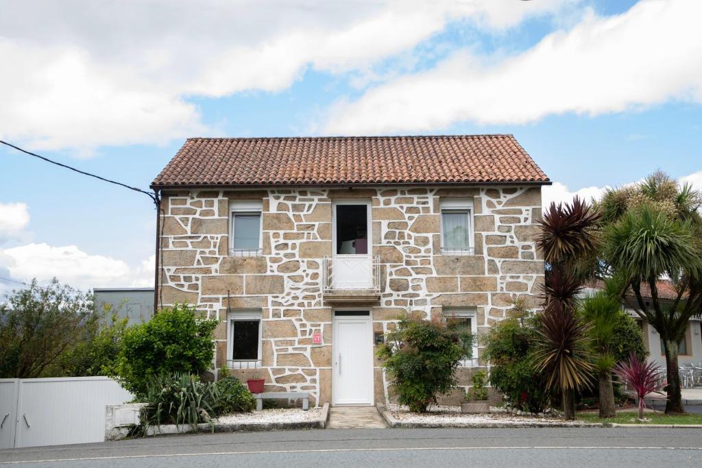 a stone house with a white door at Casa San Martiño Teo in Rua De Francos