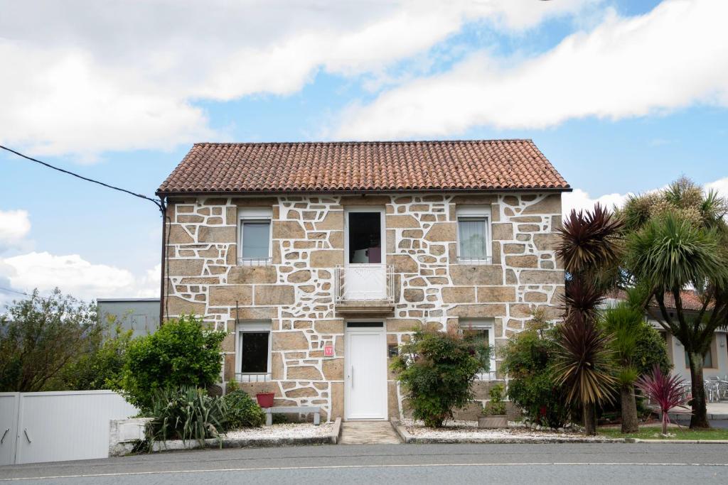 a stone house with a white door at Casa San Martiño - Teo in Rua De Francos