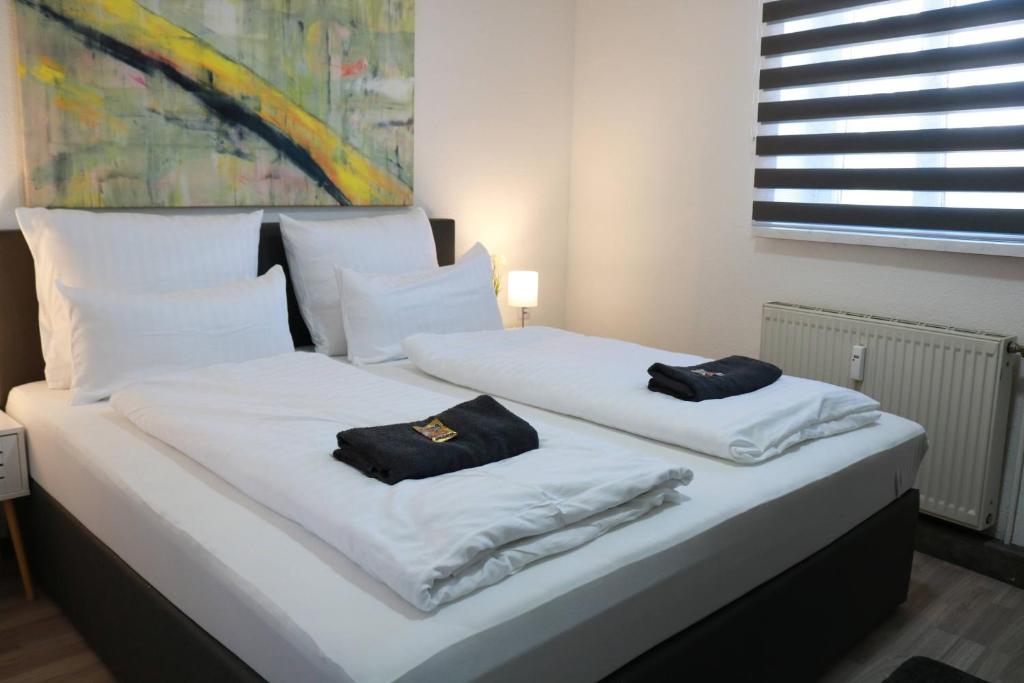 2 camas con sábanas blancas y toallas negras. en Gästehaus Prein Knittelfeld nähe Red Bull Ring, en Knittelfeld