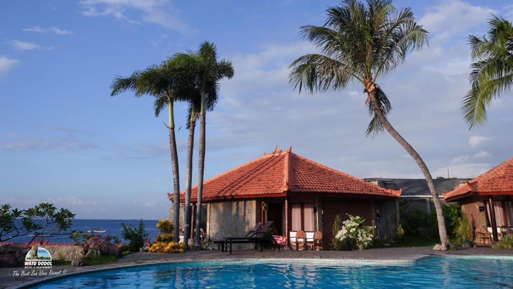 een resort met een zwembad en palmbomen bij Watu Dodol Hotel & Restaurant in Banyuwangi