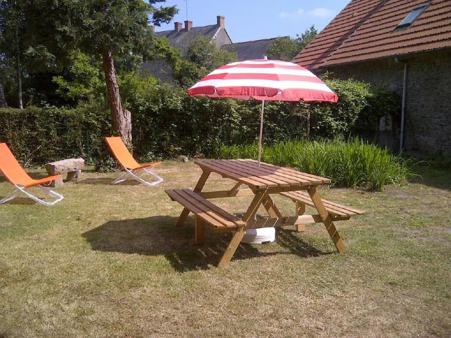 a picnic table with an umbrella and two chairs at Maison entre terre & mer in Pirou