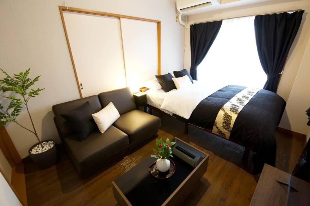 a bedroom with a bed and a couch and a table at ビスタ池上 301 in Tokyo