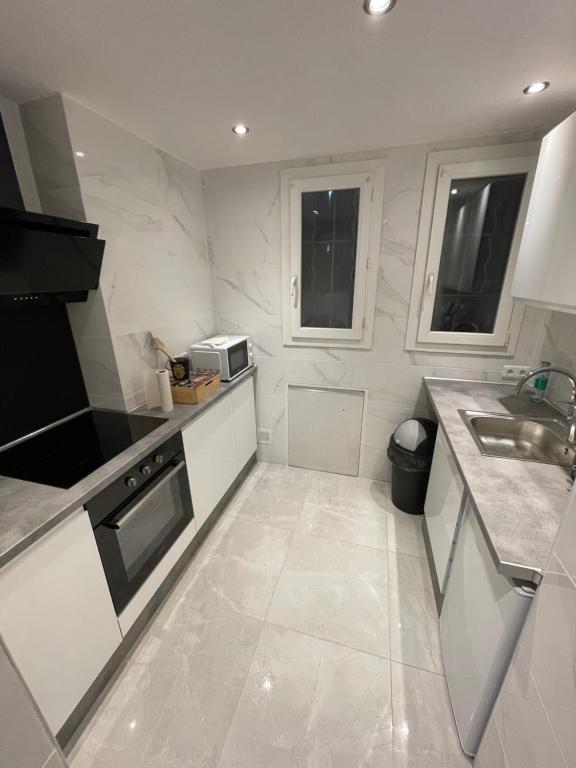 une cuisine blanche avec un évier et un micro-ondes dans l'établissement La perle marseillaise, à Marseille