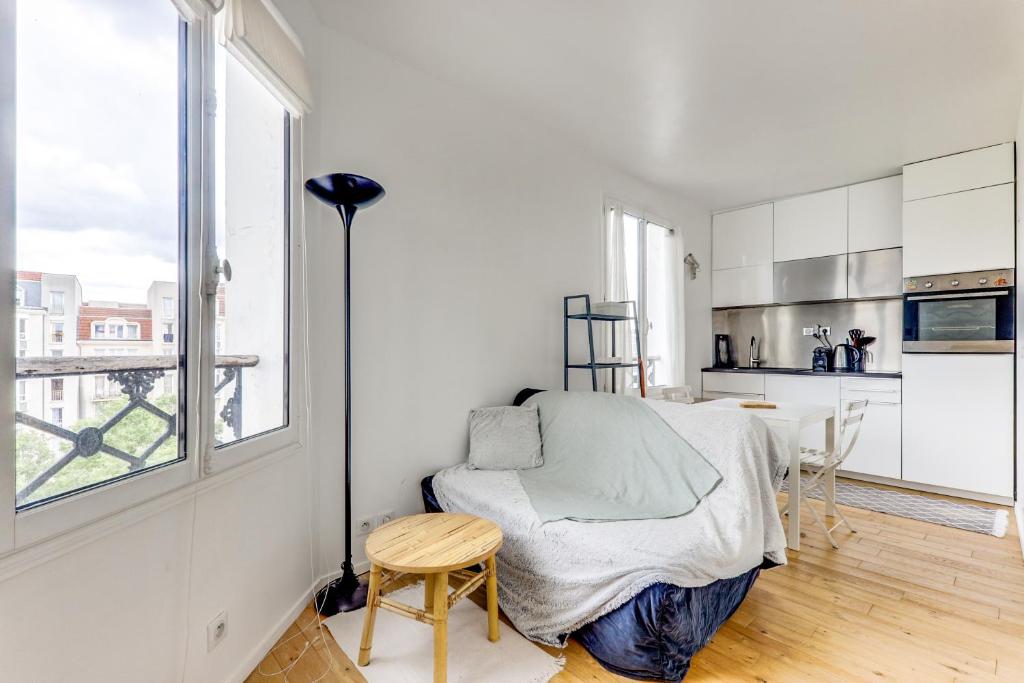 une chambre blanche avec une chaise et une cuisine dans l'établissement Appartement lumineux au dernier étage, à Paris