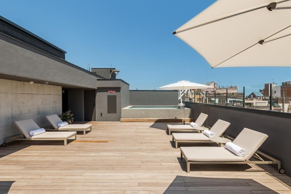 a row of lounge chairs on a rooftop patio at Room Mate Gerard in Barcelona