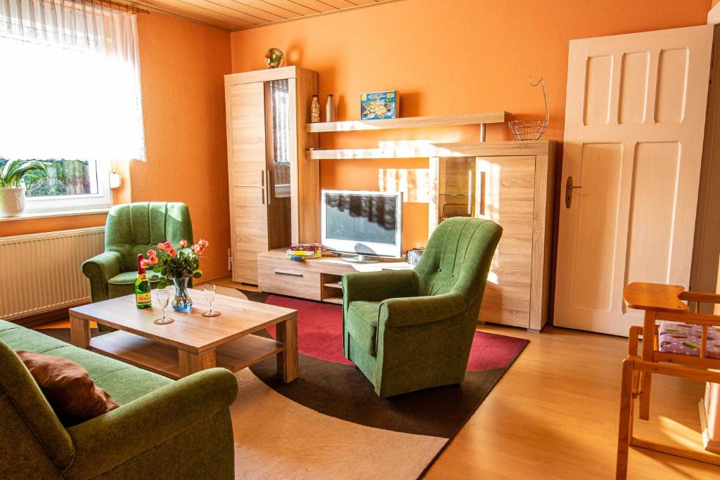 a living room with two green chairs and a television at Ferienwohnung Landmannsruh in Lubmin