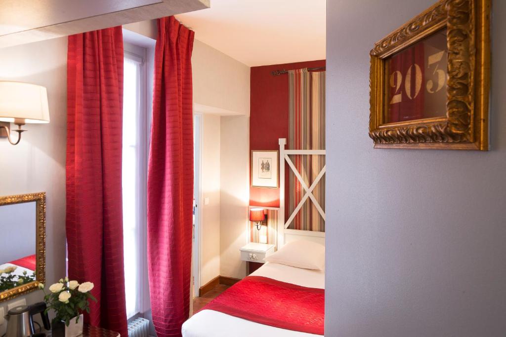 a hotel room with a bed and red curtains at Hotel Louvre Bons Enfants in Paris