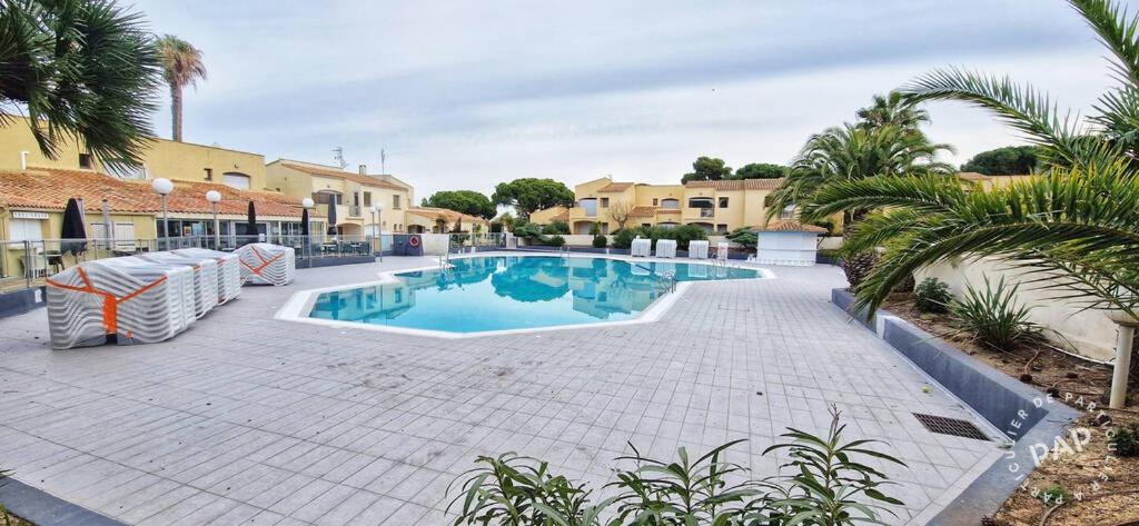 - une piscine dans une cour bordée de palmiers dans l'établissement St Loup, au Cap d'Agde