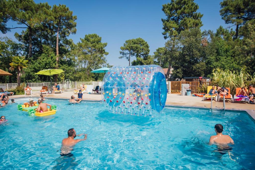 a group of people in a swimming pool with a water fountain at Camping Les Pins de la Coubre in Les Mathes