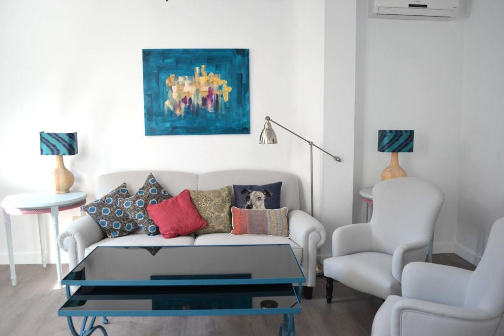 a living room filled with furniture and a painting at Casas y Patios de Sevilla in Seville