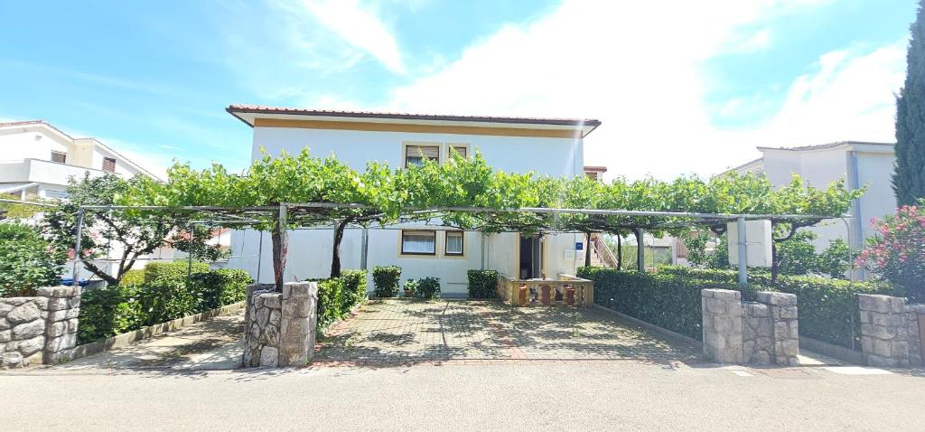 een wit huis met een pergola ervoor bij Apartments Rudolf in Krk