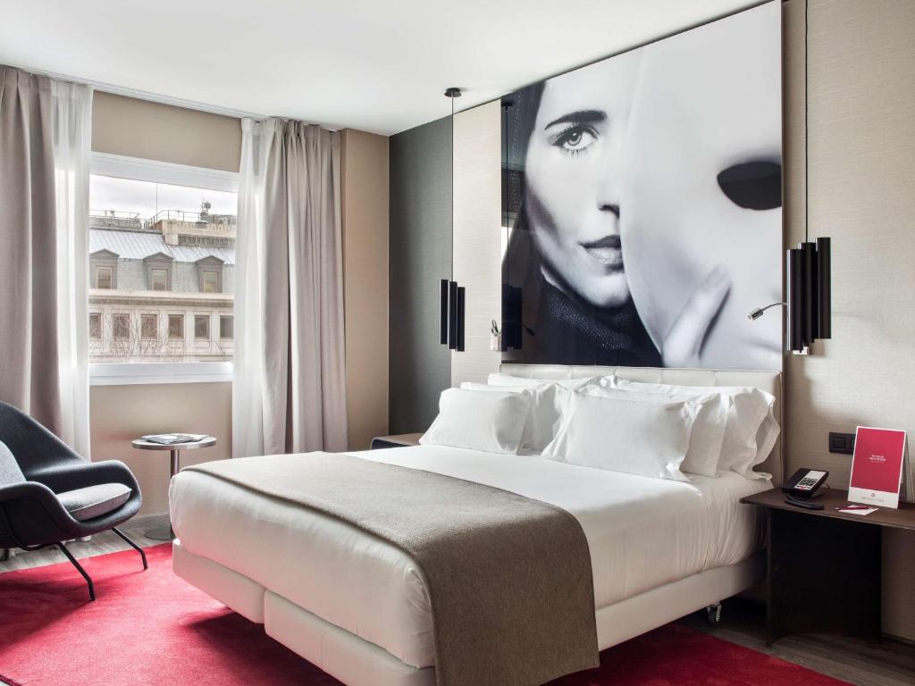 a hotel room with a bed and a large poster of a woman at NH Collection Madrid Suecia in Madrid