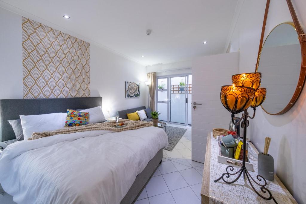 a bedroom with a large bed and a mirror at Cosy and Central in Claremont in Cape Town