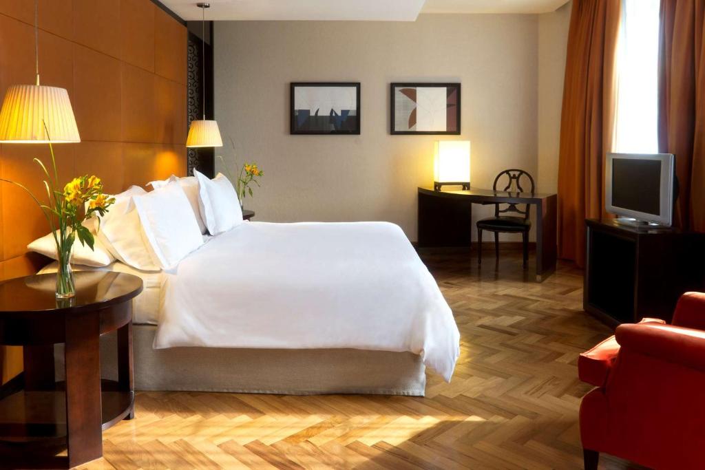 um quarto de hotel com uma cama branca e uma televisão em NH Collection Buenos Aires Lancaster em Buenos Aires