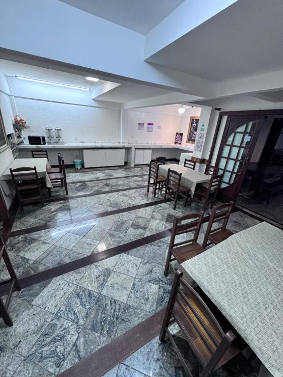 um quarto vazio com mesas e cadeiras e um quarto com uma cozinha em Flamingo Beach Pousada em Cabo Frio