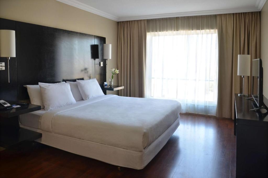 um quarto de hotel com uma cama grande e uma janela em NH Ciudad de Santiago em Santiago