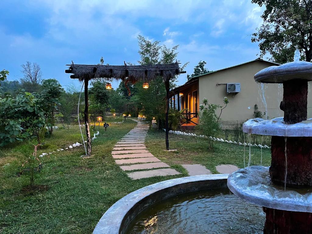 a garden with a water fountain in front of a house at Grand Narmada Homestay Resort-Bandhavgarh in Tāla
