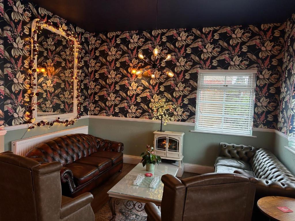 a living room with leather furniture and wallpaper at Blue Boar Inn in Atherstone