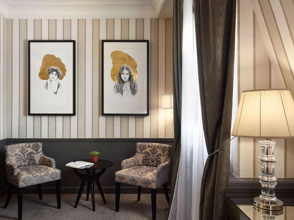 a hotel room with two chairs and paintings on the wall at Le Grand Hotel de Cabourg - MGallery Collection in Cabourg